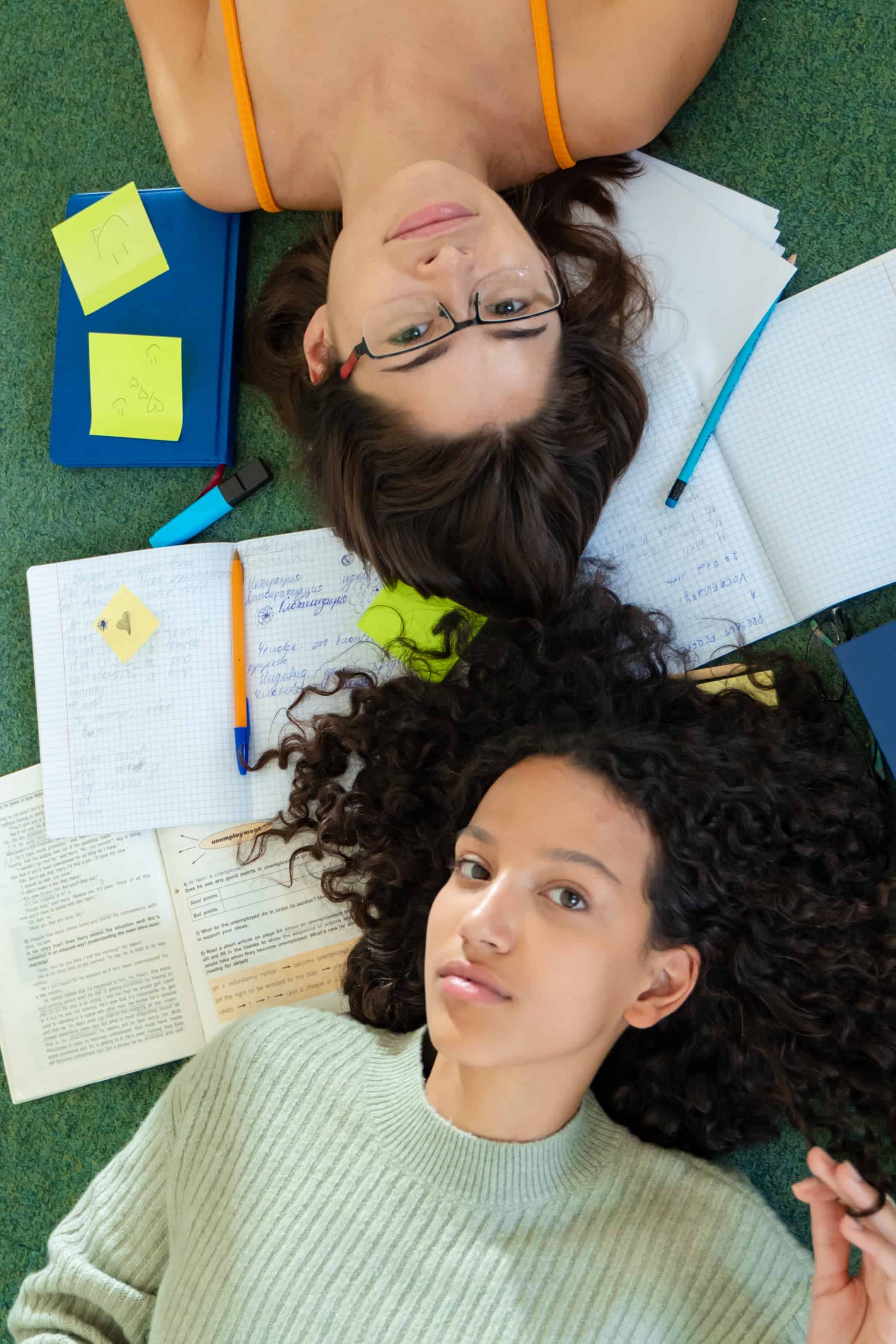Two students laying amongst their books. Balancing school, work, and home can be challenging. We're here to help!