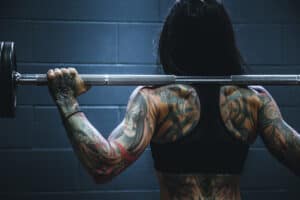 A women with tattoos lifting weights. Find your personal power. 